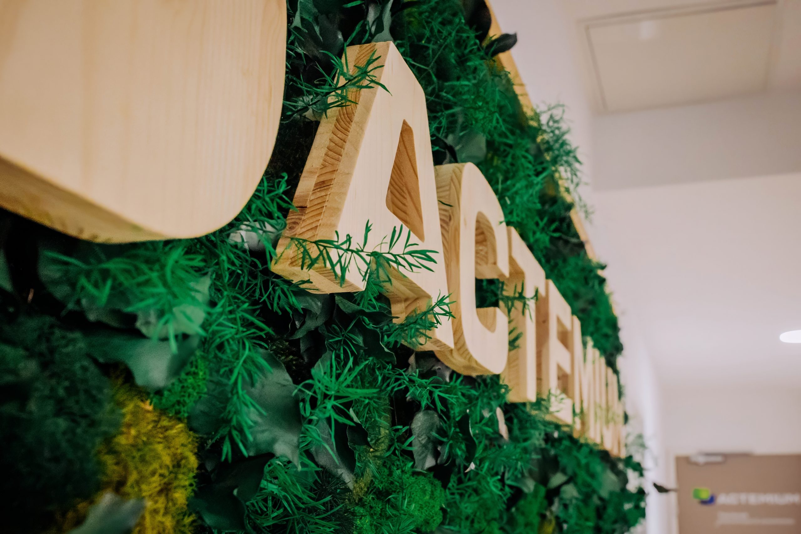 photo montrant le logo Actemium en bois sur fond végétalisé