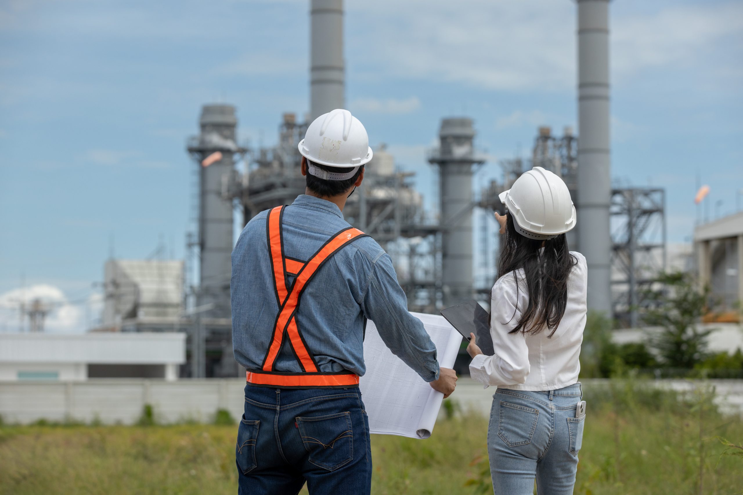 deux personnes de dos devant une usine en fonction avec un plan